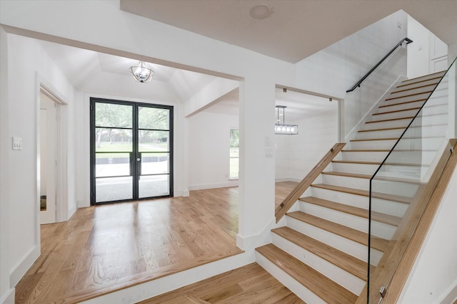 foyer featuring light wood-type flooring, a chandelier, and french doors