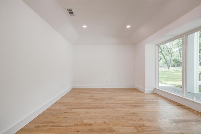 empty room with light hardwood / wood-style flooring and lofted ceiling