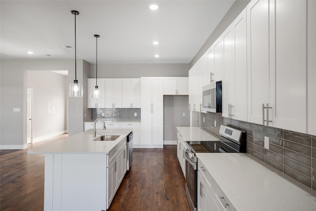 kitchen featuring pendant lighting, sink, white cabinets, a center island with sink, and stainless steel appliances