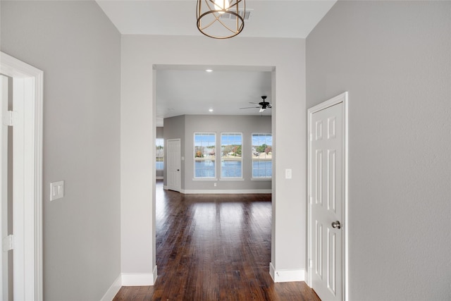 hallway with dark wood-type flooring and a notable chandelier