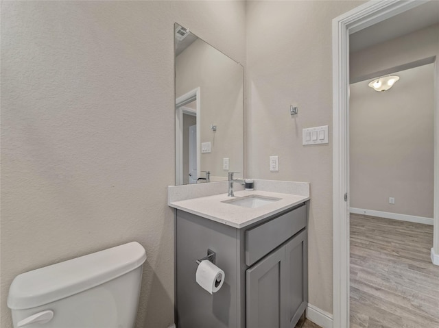 bathroom with vanity, toilet, and hardwood / wood-style floors