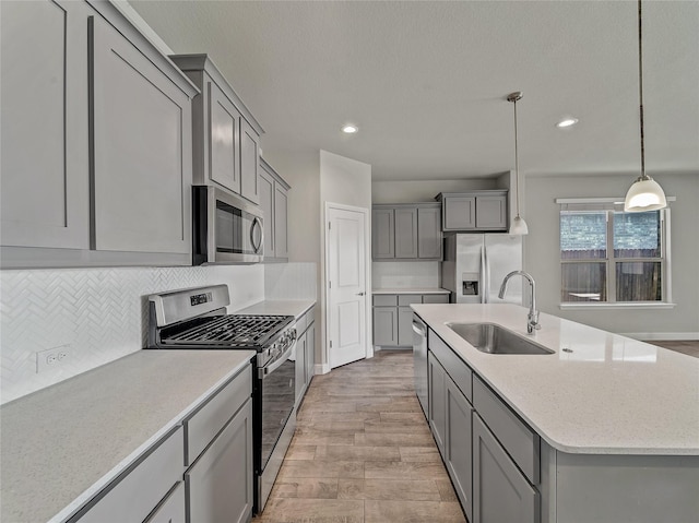 kitchen with sink, gray cabinetry, tasteful backsplash, decorative light fixtures, and stainless steel appliances