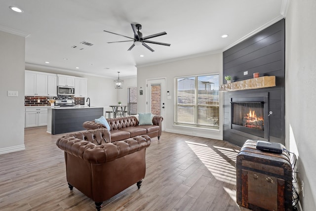 living room featuring sink, light hardwood / wood-style flooring, ceiling fan, and ornamental molding