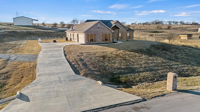 view of front of property with a garage, a front lawn, and a rural view