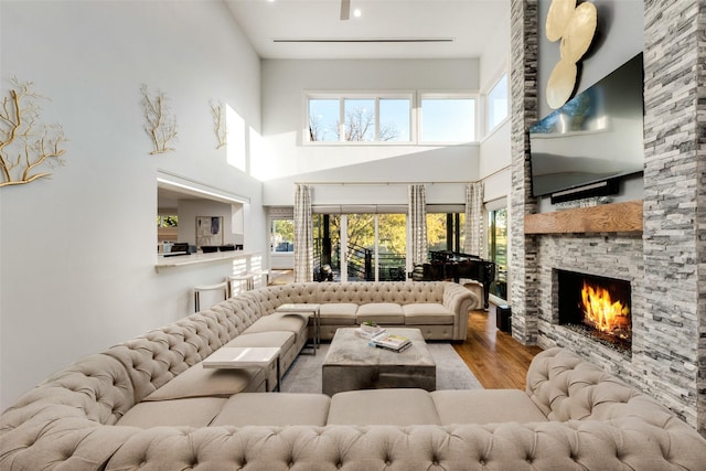 living room with light wood-type flooring, a fireplace, and a high ceiling