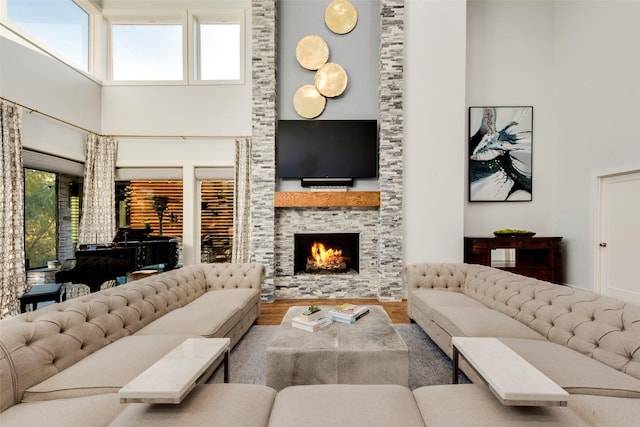 living room featuring hardwood / wood-style floors, a towering ceiling, a fireplace, and plenty of natural light