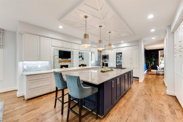 kitchen with white cabinetry, tasteful backsplash, decorative light fixtures, a large island with sink, and appliances with stainless steel finishes