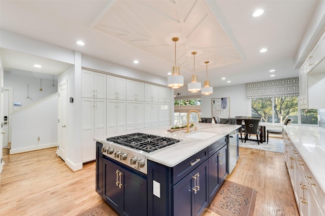 kitchen with blue cabinetry, appliances with stainless steel finishes, hanging light fixtures, light stone countertops, and white cabinets