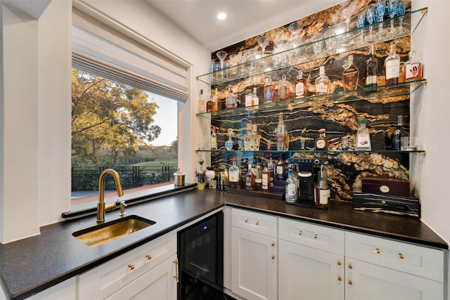 bar with white cabinetry, sink, and beverage cooler