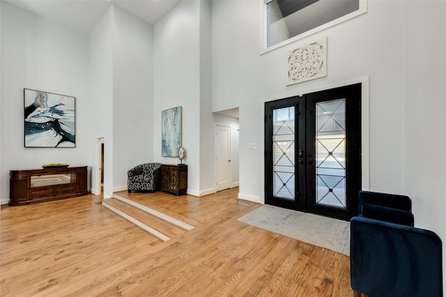 foyer entrance featuring hardwood / wood-style flooring, a high ceiling, and french doors