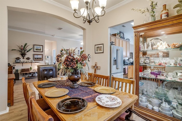 dining area with crown molding, ceiling fan with notable chandelier, and light hardwood / wood-style flooring