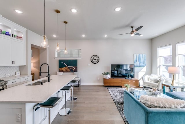 living room with sink, light wood-type flooring, and ceiling fan