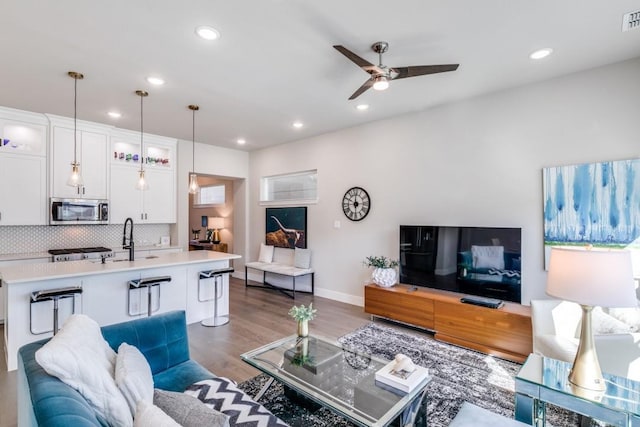 living room featuring sink, dark wood-type flooring, and ceiling fan