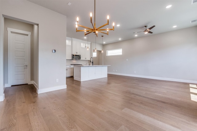 7836 Minglewood Ln, Dallas, TX 75231 - unfurnished living room featuring a chandelier, a sink, light wood-style flooring, ceiling fan, and baseboards