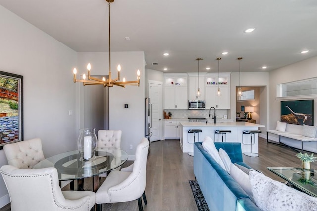 dining area with sink, a notable chandelier, and dark hardwood / wood-style floors