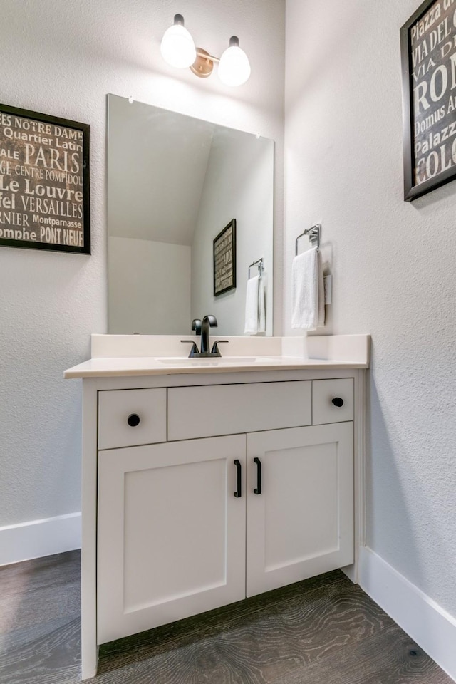 bathroom with vanity, hardwood / wood-style floors, and lofted ceiling