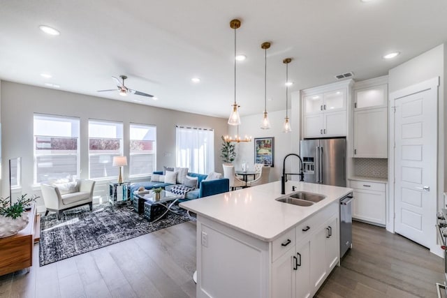 kitchen featuring hanging light fixtures, sink, white cabinets, a kitchen island with sink, and stainless steel appliances