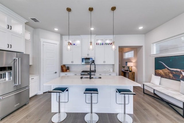 kitchen featuring tasteful backsplash, white cabinetry, hanging light fixtures, and stainless steel appliances