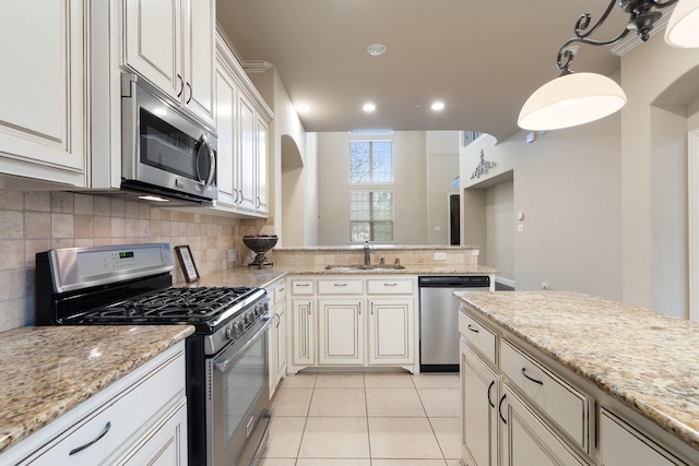 kitchen with appliances with stainless steel finishes, light tile patterned floors, sink, decorative light fixtures, and light stone counters