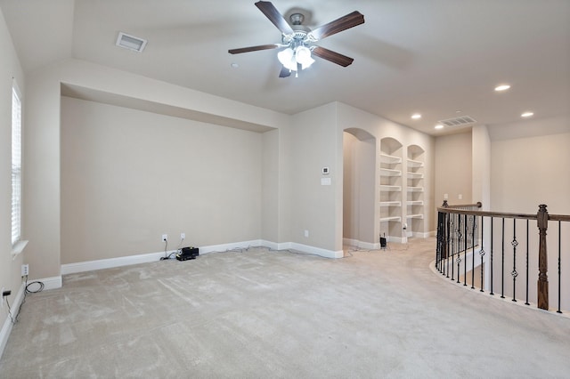 carpeted empty room featuring ceiling fan, built in features, and lofted ceiling