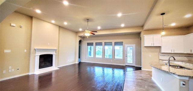 kitchen featuring pendant lighting, sink, white cabinets, tasteful backsplash, and light stone countertops