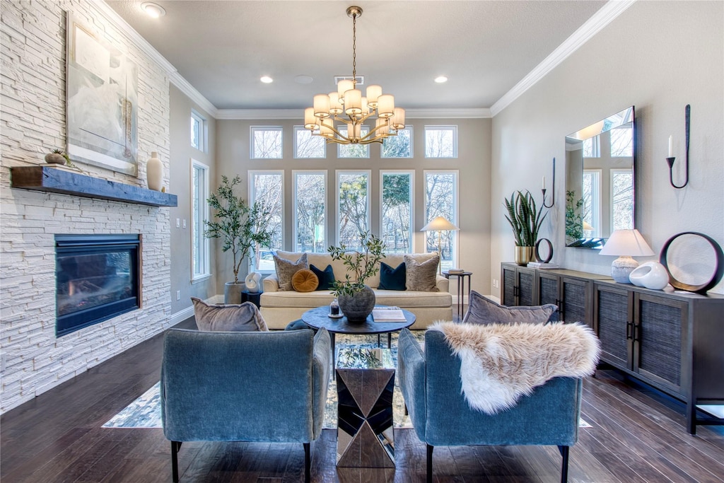 living room with dark hardwood / wood-style flooring, a notable chandelier, a stone fireplace, and ornamental molding