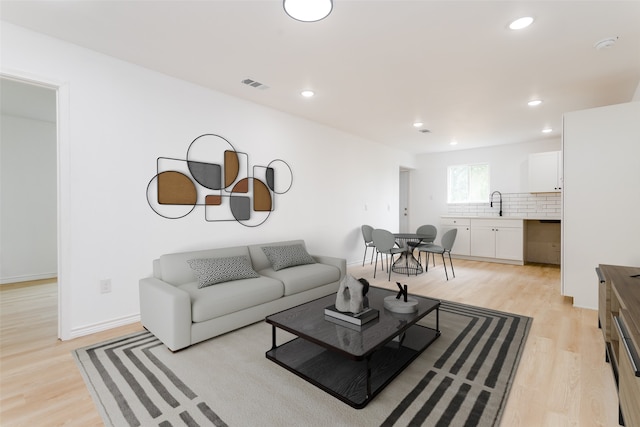 living room featuring sink and light hardwood / wood-style flooring