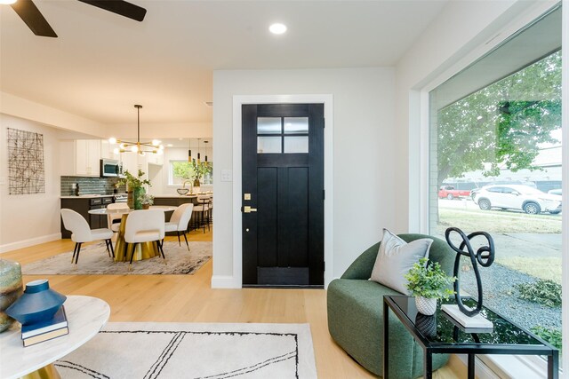 kitchen with appliances with stainless steel finishes, sink, light hardwood / wood-style flooring, pendant lighting, and a center island with sink