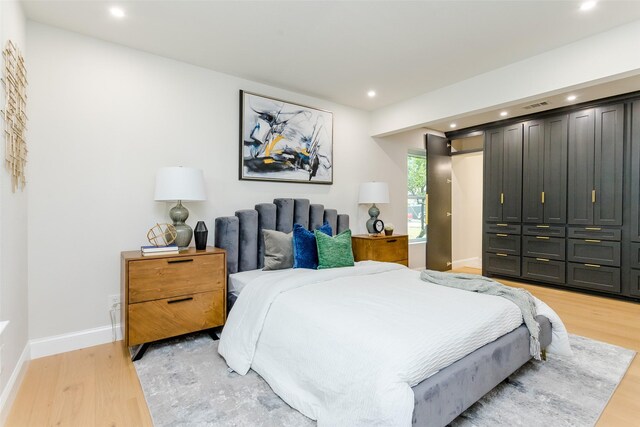 bedroom featuring light hardwood / wood-style floors and beam ceiling