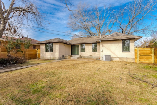 back of house featuring central AC unit and a lawn