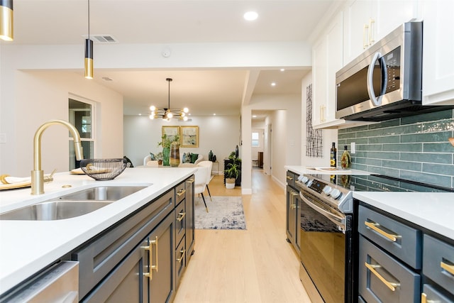 kitchen with stainless steel appliances, a sink, visible vents, white cabinetry, and light wood-type flooring