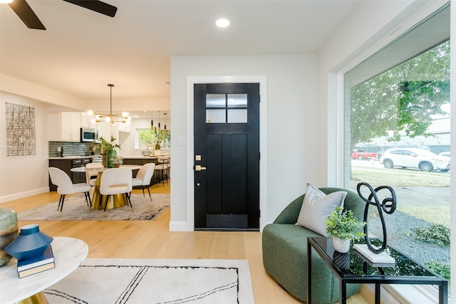 entrance foyer featuring light hardwood / wood-style floors and ceiling fan with notable chandelier