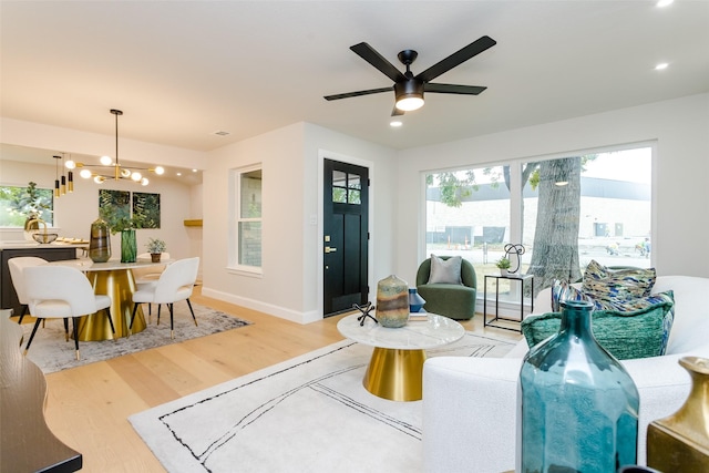 living room with light hardwood / wood-style floors and ceiling fan with notable chandelier