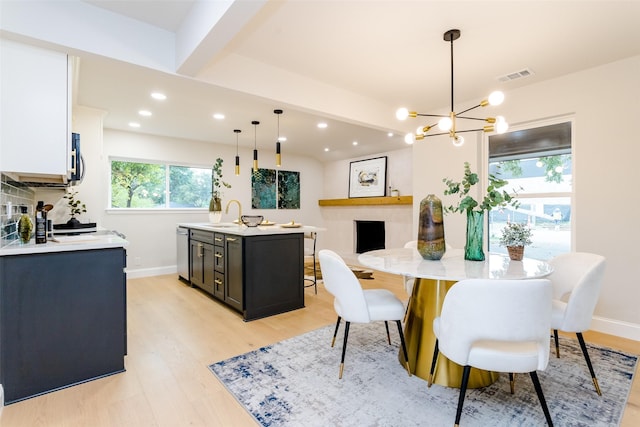 dining room with sink, light hardwood / wood-style flooring, and beamed ceiling