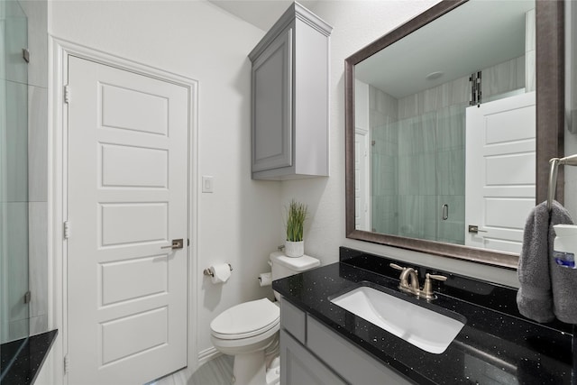 bathroom featuring vanity, toilet, and a shower with shower door