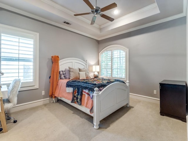 bedroom featuring ceiling fan, light colored carpet, multiple windows, and a tray ceiling