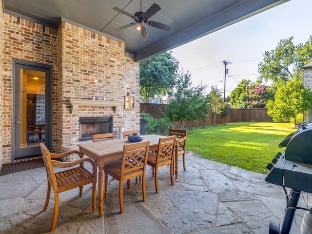 view of patio with an outdoor brick fireplace, grilling area, and ceiling fan