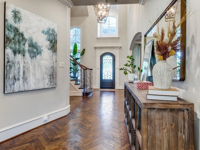 entrance foyer with dark parquet floors, a high ceiling, and an inviting chandelier