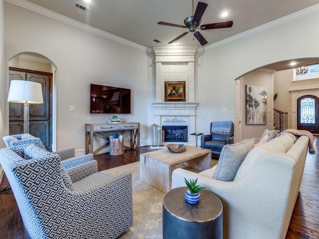 living room featuring a large fireplace, ceiling fan, crown molding, and hardwood / wood-style floors