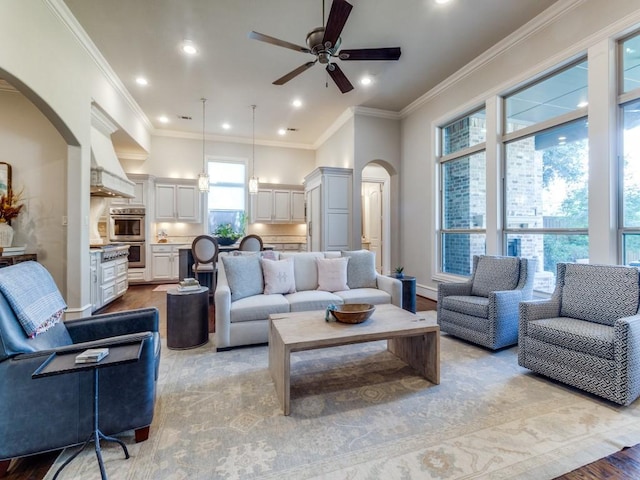 living room with ceiling fan, crown molding, and plenty of natural light