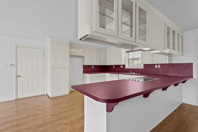 kitchen featuring black electric cooktop, white cabinetry, a breakfast bar area, and kitchen peninsula