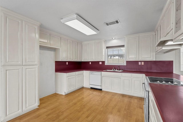 kitchen featuring stainless steel gas range oven, white cabinets, and white dishwasher