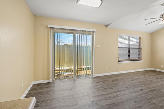 unfurnished room with lofted ceiling, a healthy amount of sunlight, dark hardwood / wood-style floors, and ceiling fan