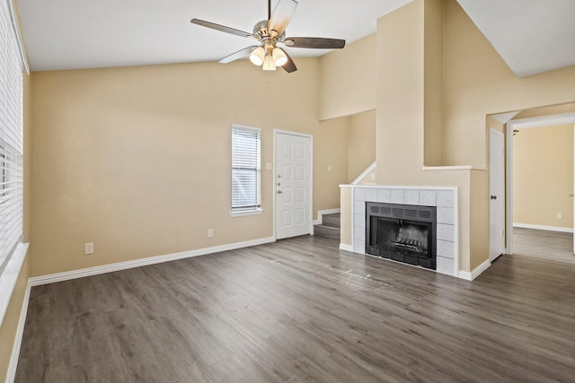 unfurnished living room featuring ceiling fan, vaulted ceiling, dark hardwood / wood-style floors, and a fireplace