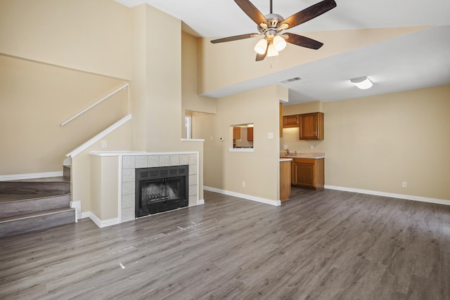 unfurnished living room featuring a fireplace, light wood-type flooring, sink, and ceiling fan