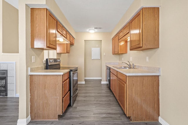 kitchen featuring sink, hardwood / wood-style floors, appliances with stainless steel finishes, and a tile fireplace