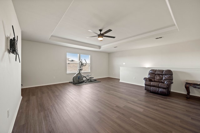 workout room with a tray ceiling, dark wood-style flooring, visible vents, and baseboards