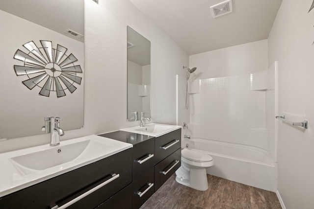 bathroom with toilet, wood finished floors, a sink, and visible vents