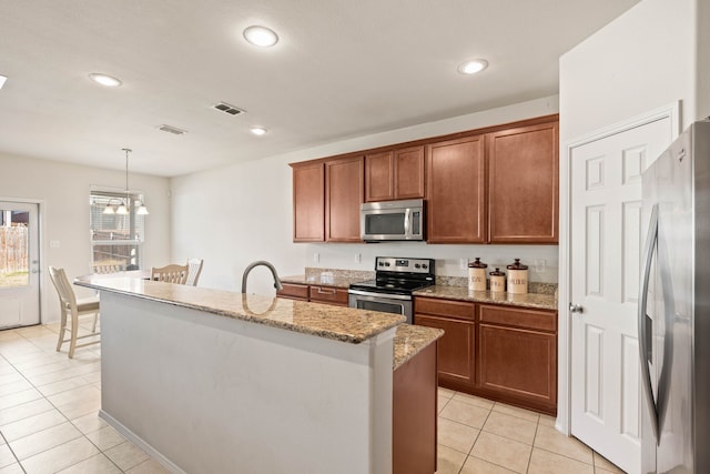 kitchen featuring light stone counters, a center island with sink, light tile patterned floors, stainless steel appliances, and visible vents