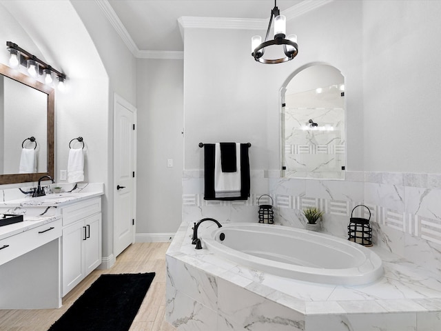 bathroom with tiled bath, an inviting chandelier, vanity, and ornamental molding